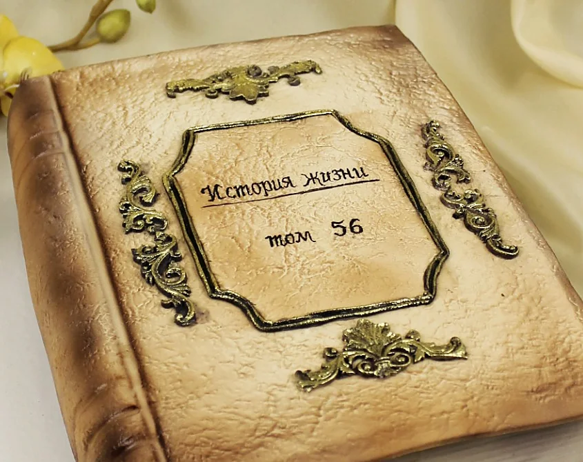 Обложка торта-книги с надписью «История жизни. Том 56» и орнаментом